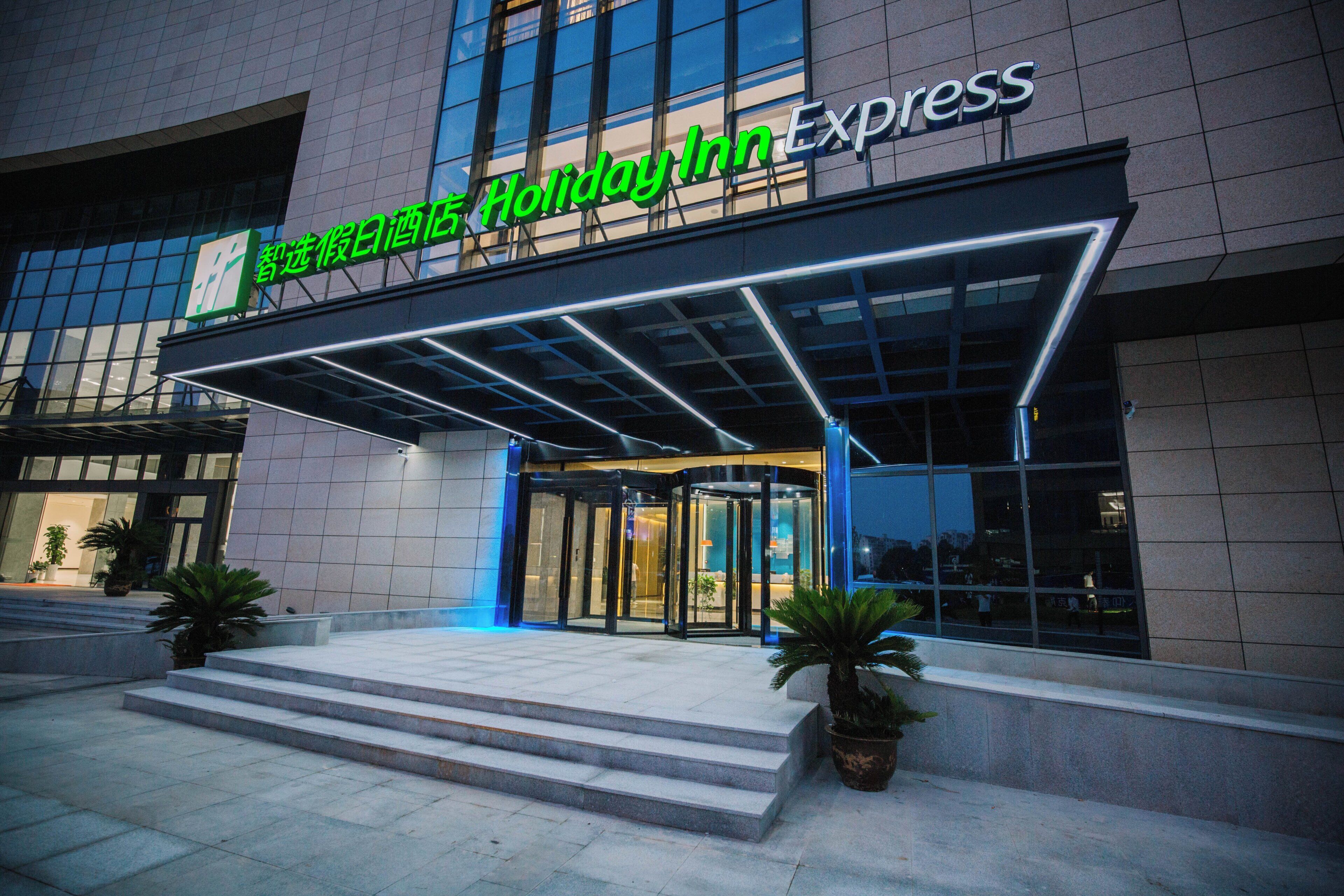 De gevel van een Holiday Inn Express hotel met een glazen entree en een overdekt portaal.