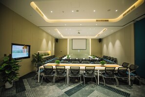Une salle de conférence équipée d’une longue table, de chaises, d’un écran de projection et d’un grand écran.