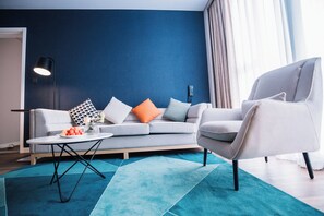A modern living room with a grey sofa, a white armchair, a coffee table, and a blue accent rug. - Holiday Inn Express Ningbo Fenghua by IHG (Ningbo)