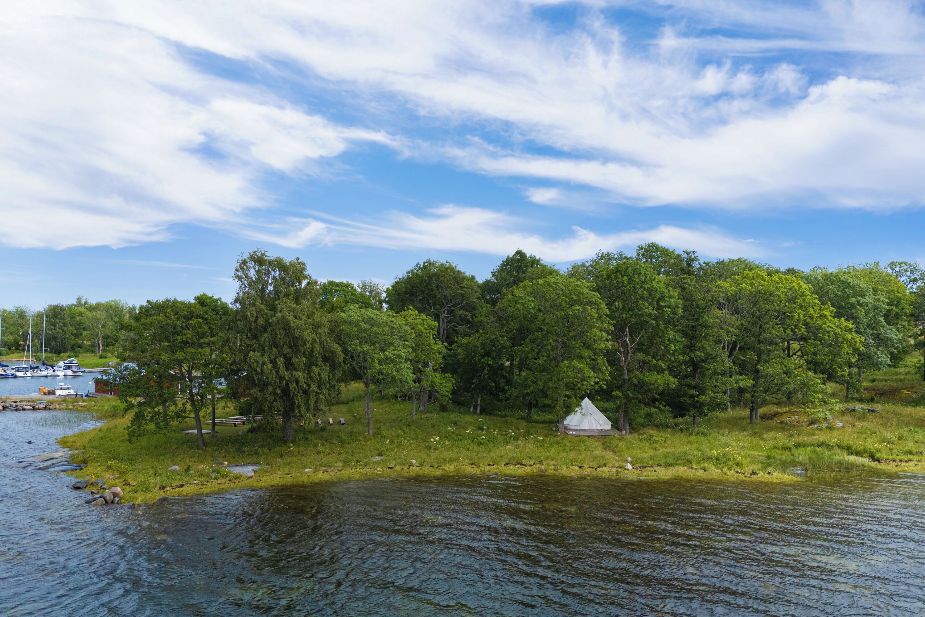 A lakeside view with a tent and boats.