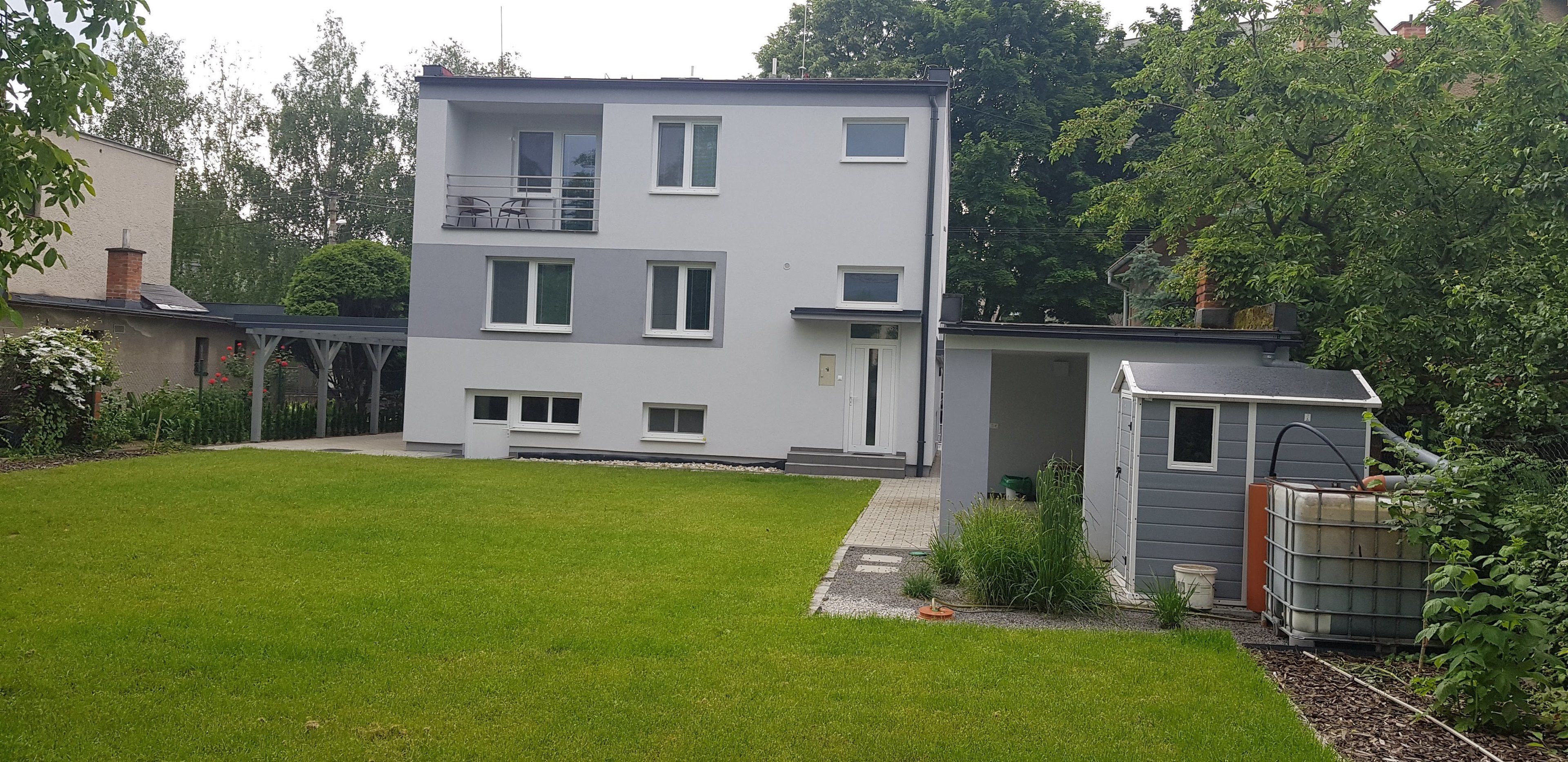A modern two-story house with a flat roof, a small attached garage, and a well-maintained lawn.