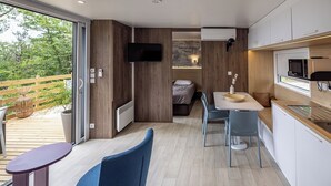 Un espace de vie moderne et compact comprenant une cuisine, un coin repas et une chambre.