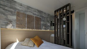 Une chambre moderne avec un grand lit, une tête de lit en bois et une armoire intégrée dotée d’un miroir.