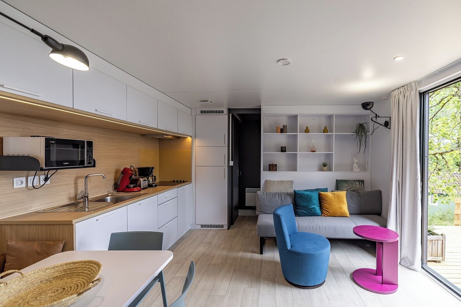 A modern kitchen with built-in appliances, a dining area with a table and chairs, and a living space with a sofa and a coffee table.