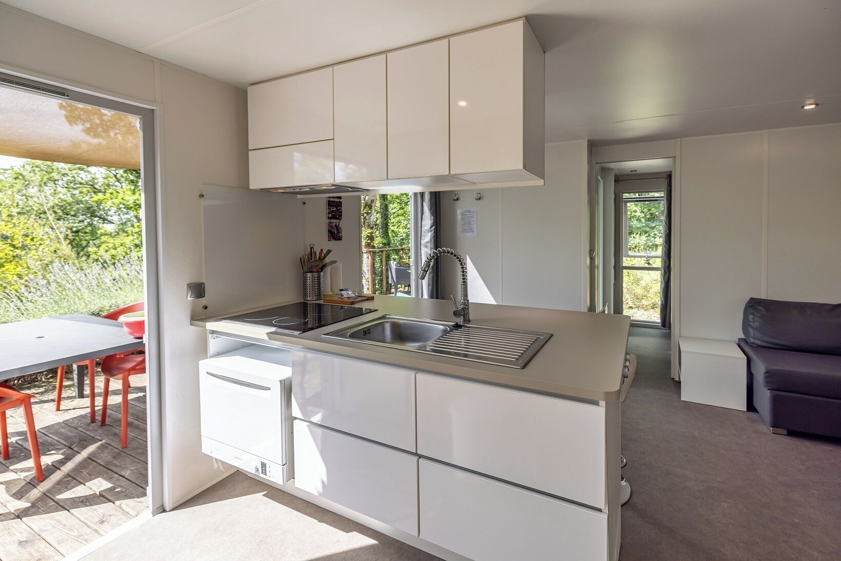 Une cuisine moderne avec des meubles blancs, un évier en acier inoxydable et une cuisinière encastrée.