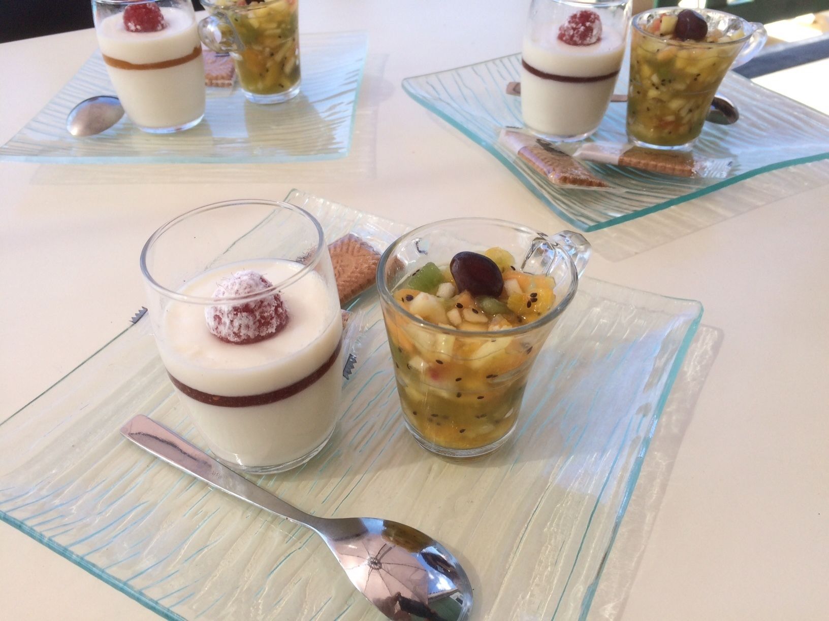 A table with three dessert glasses, each with a different dessert and a spoon.
