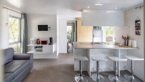 Une cuisine moderne dotée d’un îlot central, de tabourets de bar et d’un téléviseur à écran plat fixé au mur.