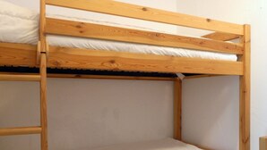 A bunk bed with white bedding and wooden frame.