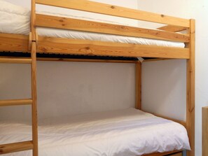 A bunk bed with white bedding and wooden frame.