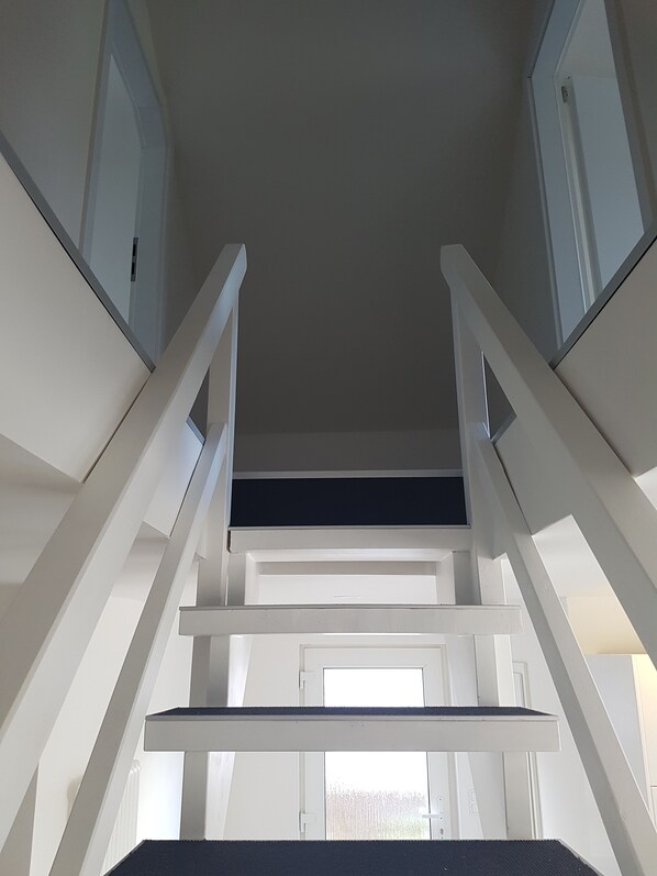 A staircase with white railings leading to a landing. - Haus Lena 2 - Vacation near the Baltic Sea - Now with e-charging station! (Pansdorf)