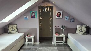 Un dormitorio acogedor en el ático, con techo inclinado, dos camas, una mesita y una puerta decorativa.