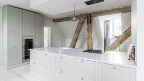 A modern kitchen with white cabinetry, a marble countertop, and a wooden beam ceiling. - Majestic 300m2 Apartment (Copenhagen)