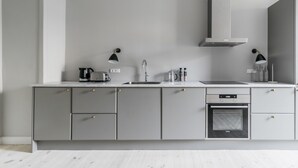 A modern kitchen with grey cabinetry, a built-in oven, and a stainless steel range hood. - Apartment with Private Terrace (Copenhagen)
