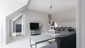 A modern loft apartment with a dining area, kitchen, and a large TV. - Apartment with Private Terrace (Copenhagen)