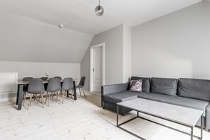 A modern living space with a dining area, grey sofa, and a minimalist design.