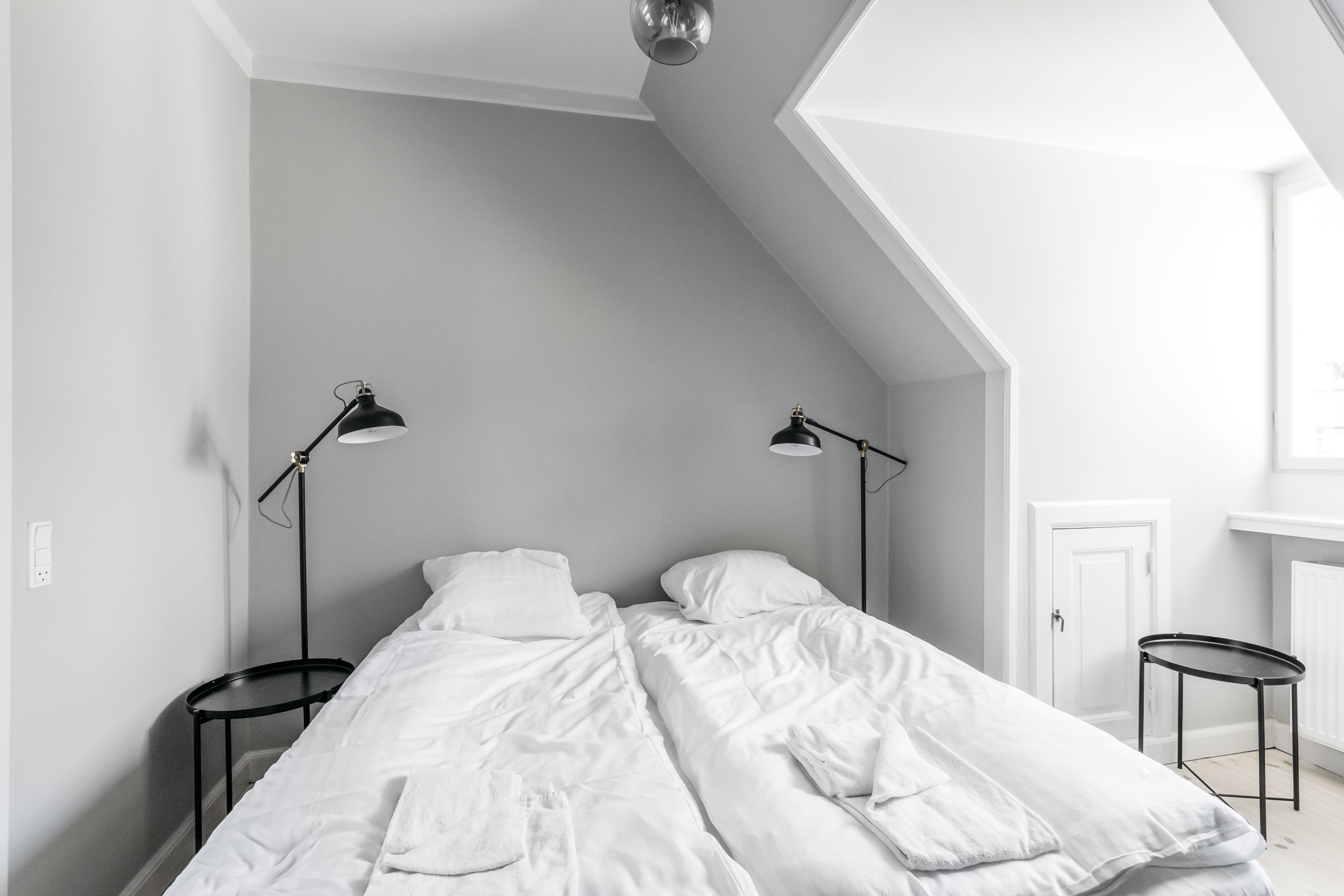 A bedroom with a sloped ceiling, two bedside tables, and two lamps.