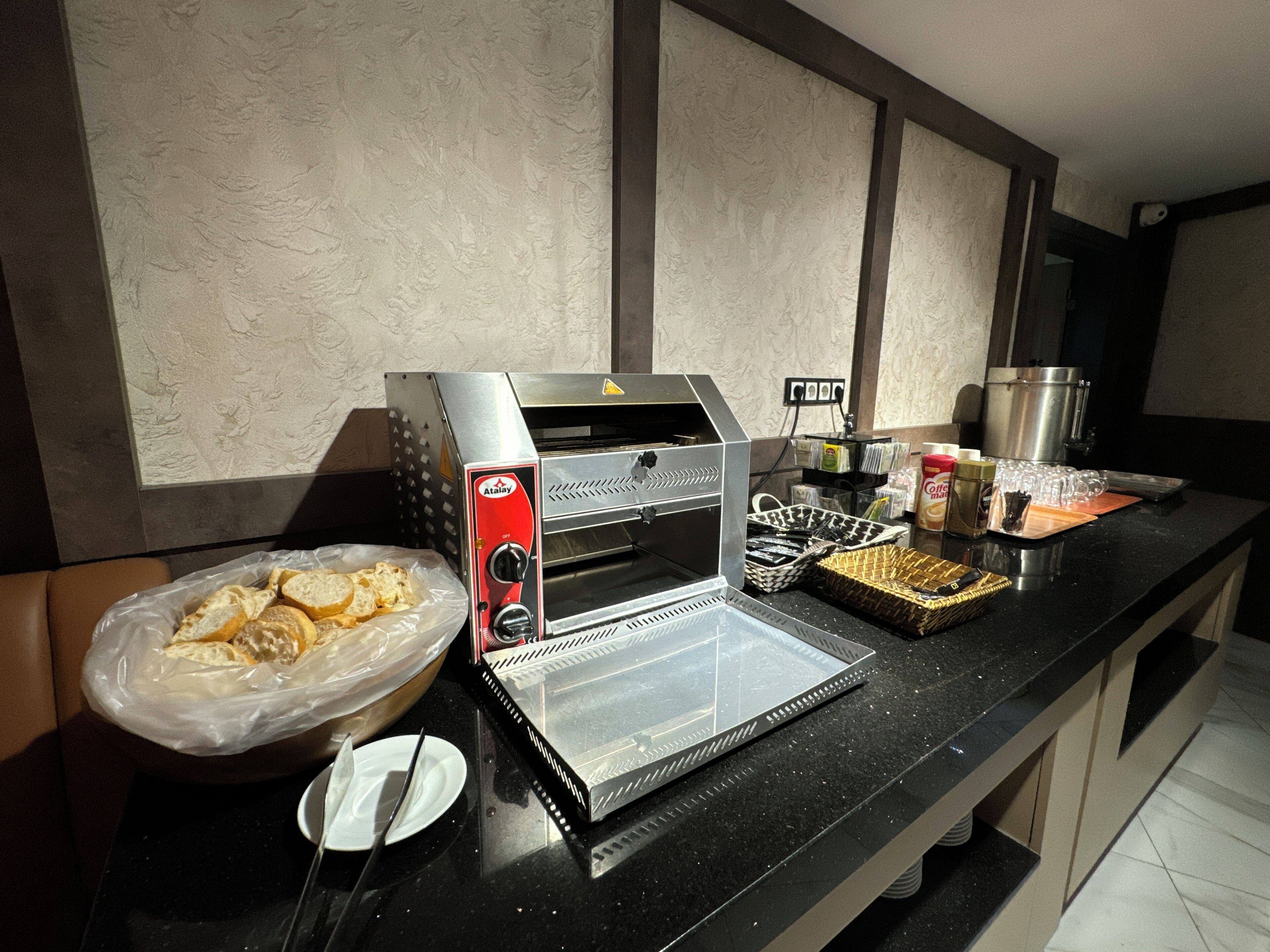 Una cocina con cafetera, una cesta de pan, hervidor y tetera.