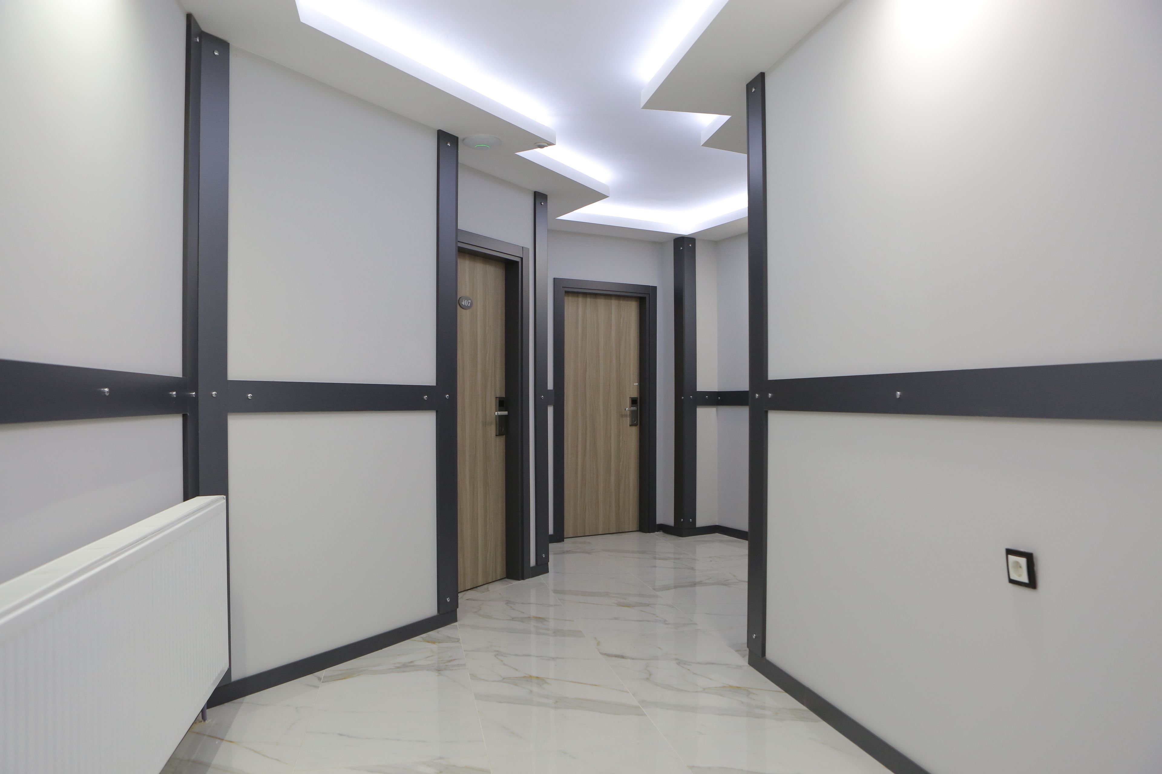 A hallway with white walls, dark trim, and a marble floor.