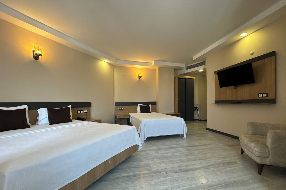 A hotel room with two beds, a TV, and a chair.
