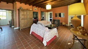 Un dormitorio acogedor con techo de madera, un armario grande, una cama con edredón estampado y una mesa con lámpara.