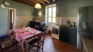 Una cocina con vigas de madera, una mesa de comedor con platos y vasos, una estufa y un refrigerador.