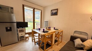 A compact living space with a kitchenette, a dining area, and a sofa. - Cozy 1-Bedroom Apt in Bernex - Ski-In/Ski-Out, WiFi, Pet-Friendly, Near Evian & Lake Geneva (Bernex)
