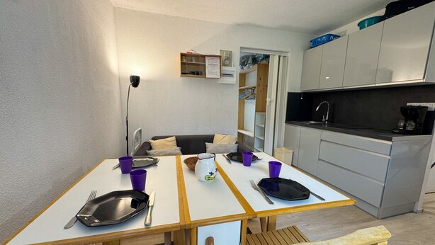 A compact kitchen with a dining table set for two, a small refrigerator, and a microwave. - Cozy 1-Bedroom Apt in Bernex - Ski-In/Ski-Out, WiFi, Pet-Friendly, Near Evian & Lake Geneva (Bernex)