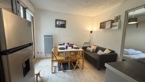 A compact living space with a kitchenette, a dining area, and a sofa. - Cozy 1-Bedroom Apt in Bernex - Ski-In/Ski-Out, WiFi, Pet-Friendly, Near Evian & Lake Geneva (Bernex)