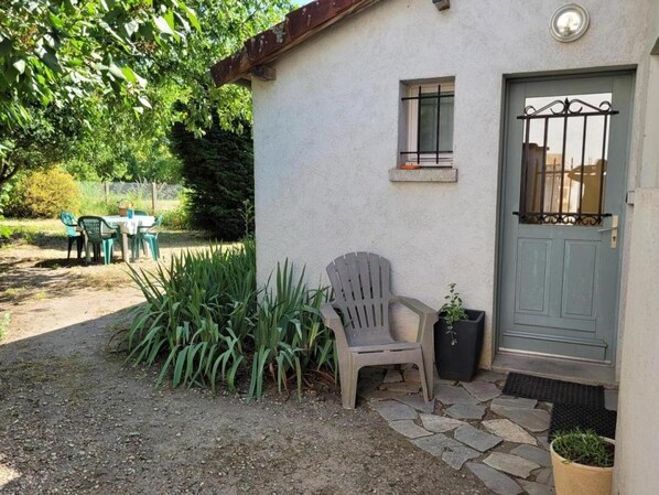 A house with a stone pathway leading to a door, a chair, and a table with chairs outside. - 2-bedroom house with enclosed garden in Sologne, pets allowed (Aurouer)