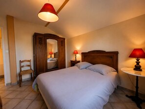 A bedroom with a bed, two bedside lamps, a wooden wardrobe, a chair, and a small round table. - 2-bedroom house with enclosed garden in Sologne, pets allowed (Aurouer)