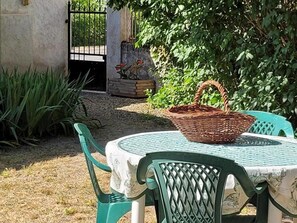 A table with a woven basket, a green chair, and a tablecloth with a pattern. - 2-bedroom house with enclosed garden in Sologne, pets allowed (Aurouer)
