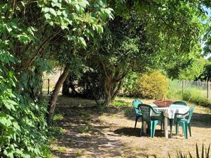 An outdoor seating area with a table and chairs under a tree. - 2-bedroom house with enclosed garden in Sologne, pets allowed (Aurouer)
