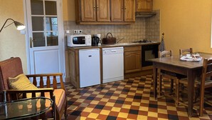 Una cocina compacta con armarios de madera, microondas, lavavajillas y un comedor con piso de cuadros.
