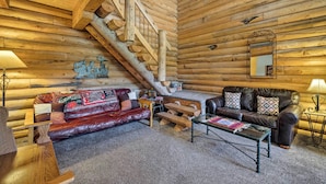 A log cabin interior with a wooden staircase, leather sofa, and a coffee table. - Pet-Friendly Moab Cabin w/ Mtn Views & BBQ! (Moab)