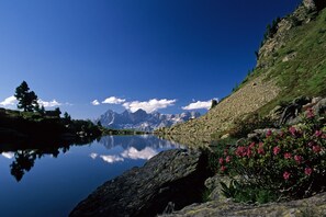 A serene lake with mountains in the background, surrounded by rocky terrain and greenery. - Hotel Appartement Hochkönig (Ramsau am Dachstein)
