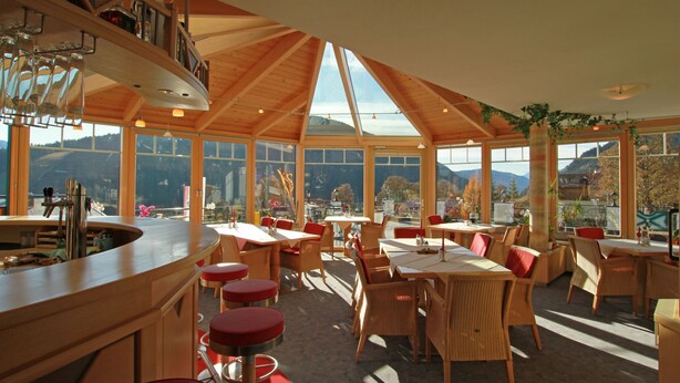 Un restaurante con techo alto y ventanas amplias que ofrecen vistas a la montaña.