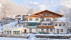 Un edificio de madera de varios pisos con balcones, un centro de bienestar y vistas a montañas nevadas.