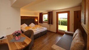 Una habitación de hotel con cama, escritorio con silla, sofá y ventana con cortinas.