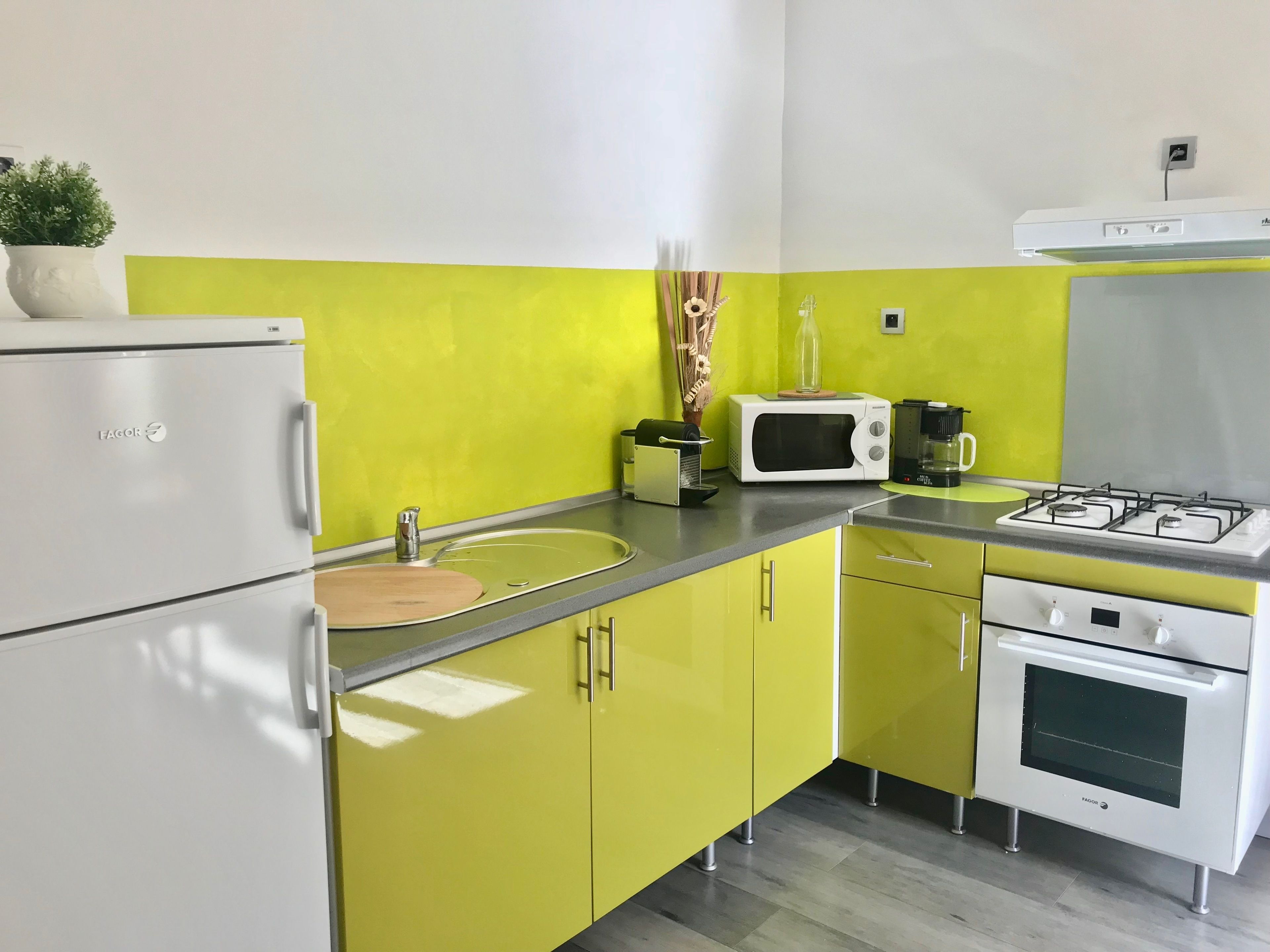 A kitchen with a refrigerator, microwave, stove, and sink.
