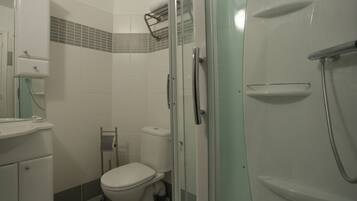 Een badkamer met toilet, wastafel en een douchecabine met glazen wanden.