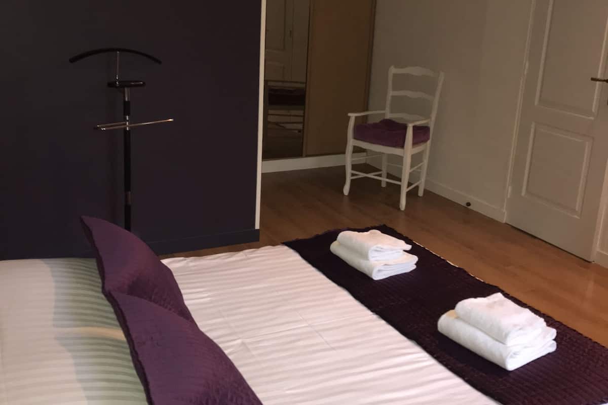 Un dormitorio con una cama, una silla, perchero y una puerta.