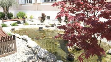 Um jardim com lago, pedras e um banco.