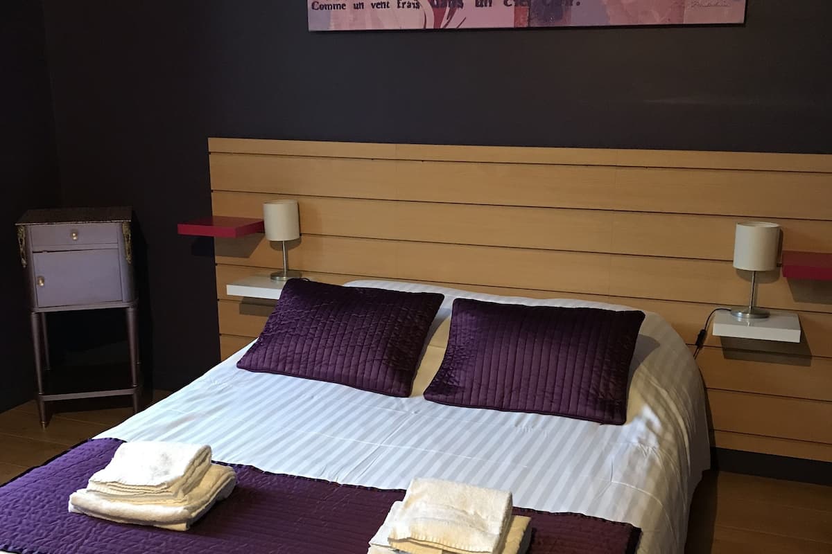 Una habitación de hotel con una cama, dos mesitas de noche y una obra de arte en la pared.