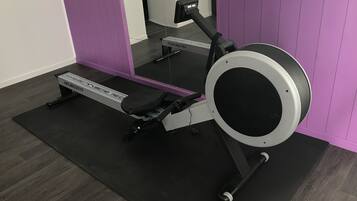 A stationary bike with a digital display, positioned in a room with purple walls and a wooden floor.