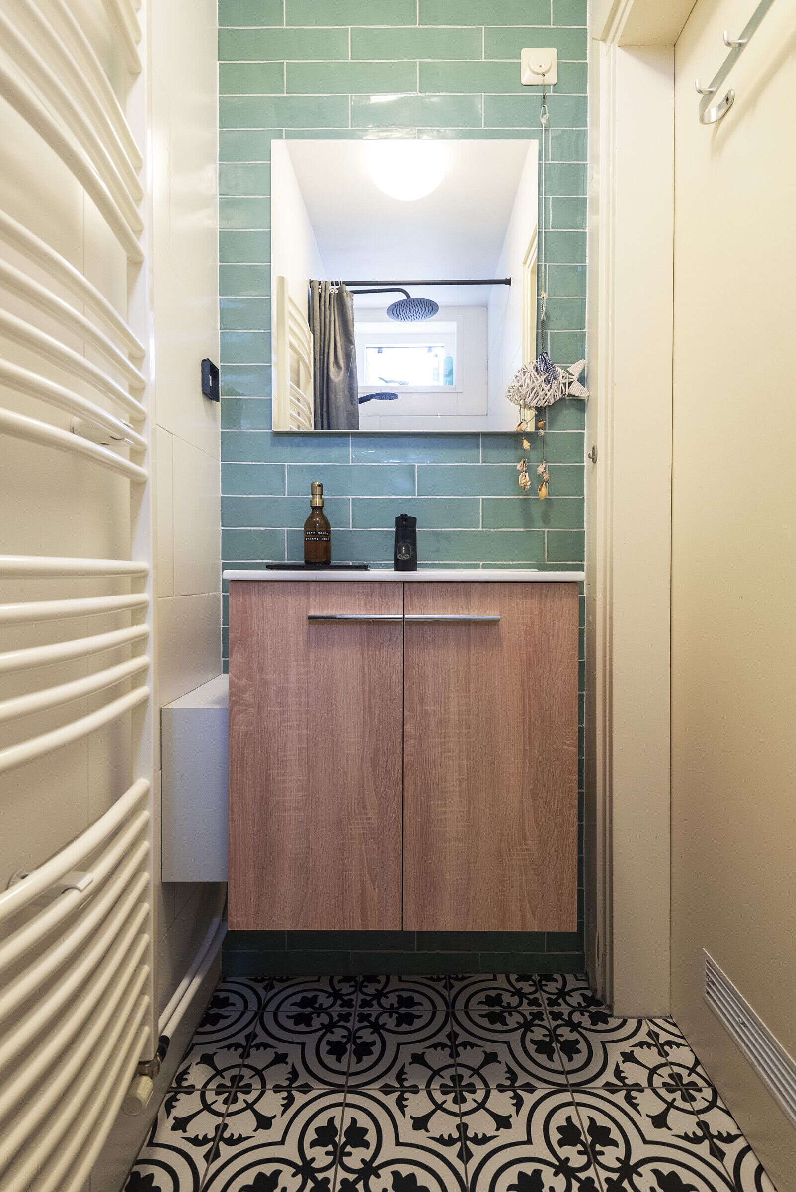 A bathroom with a wooden vanity, a mirror, and a tiled backsplash.