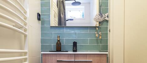 A bathroom with a wooden vanity, a mirror, and a tiled backsplash.