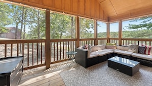 A covered outdoor seating area with a wooden deck, a sofa set, and a small table. - 2BR lodge at Stonebridge Resort near Silver Dollar City. (Branson West)