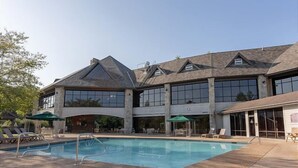 A two-story building with a swimming pool, outdoor seating, and large windows. - 2BR lodge at Stonebridge Resort near Silver Dollar City. (Branson West)
