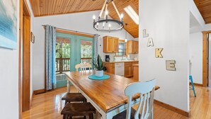 A wooden dining table with chairs, a chandelier, and a view of the outdoors. - 2BR lodge at Stonebridge Resort near Silver Dollar City. (Branson West)