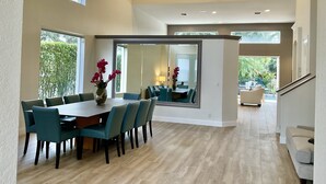 A spacious dining area with a long table and chairs, a vase with flowers, and a large mirror reflecting the room. - Pristine Home in Golf Community 3 Bedroom/3.5 Bathroom (West Palm Beach)